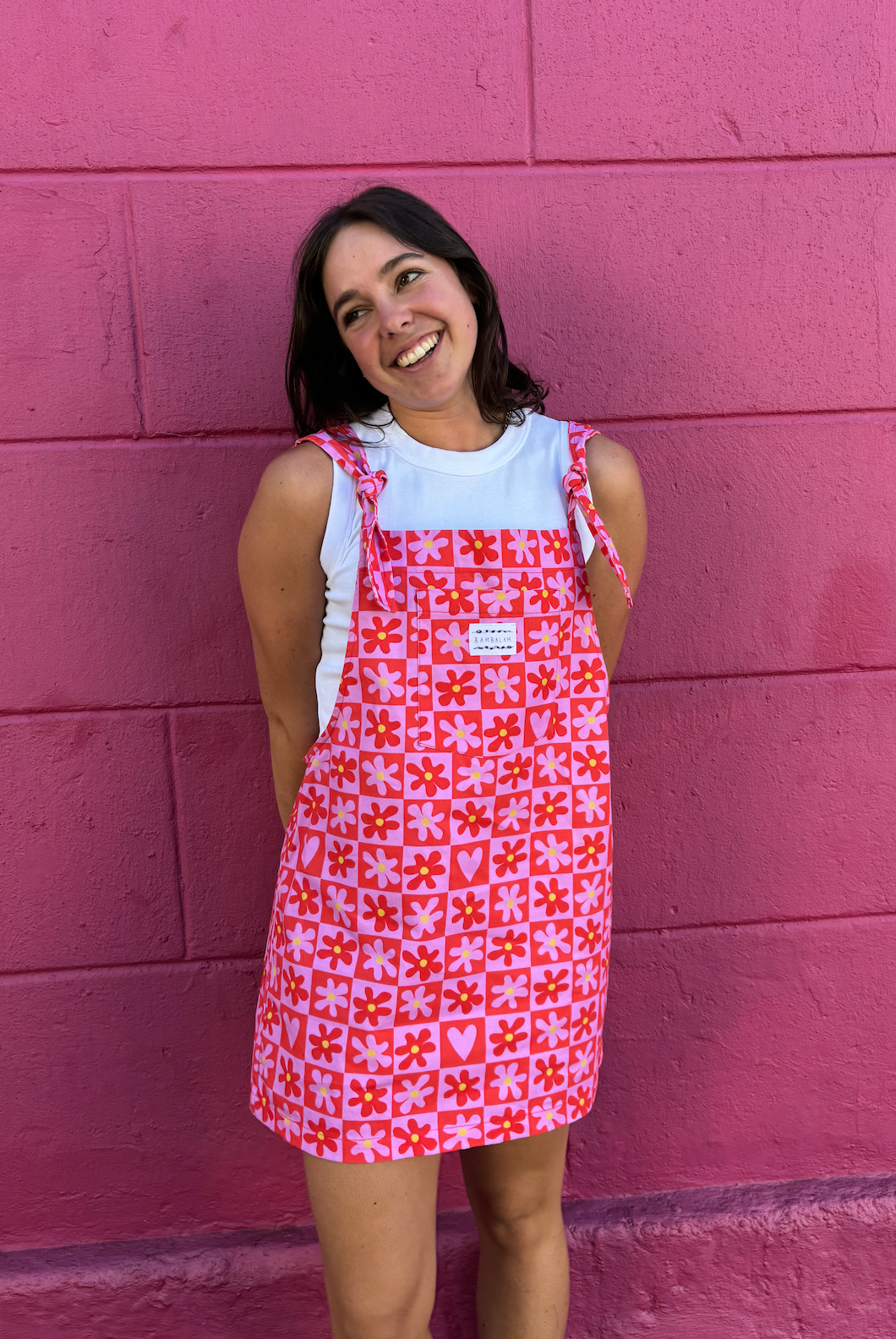 Love is the Honey dress dungaree. Pink and Red checkered pattern with flowers. Model wearing size: Medium