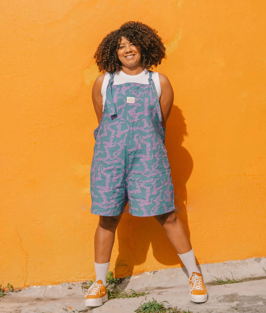 Person wearing a blue crocodile patterned overalls against an orange wall